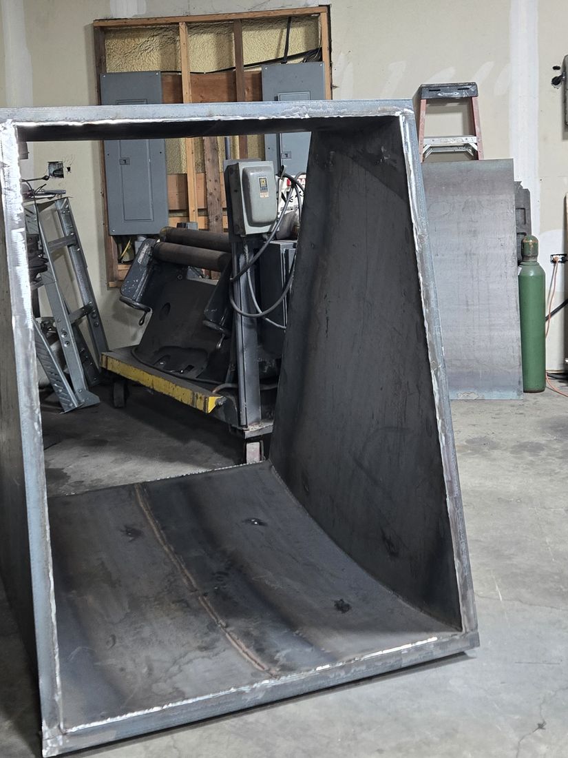 A large welded steel chute standing on the shop floor.