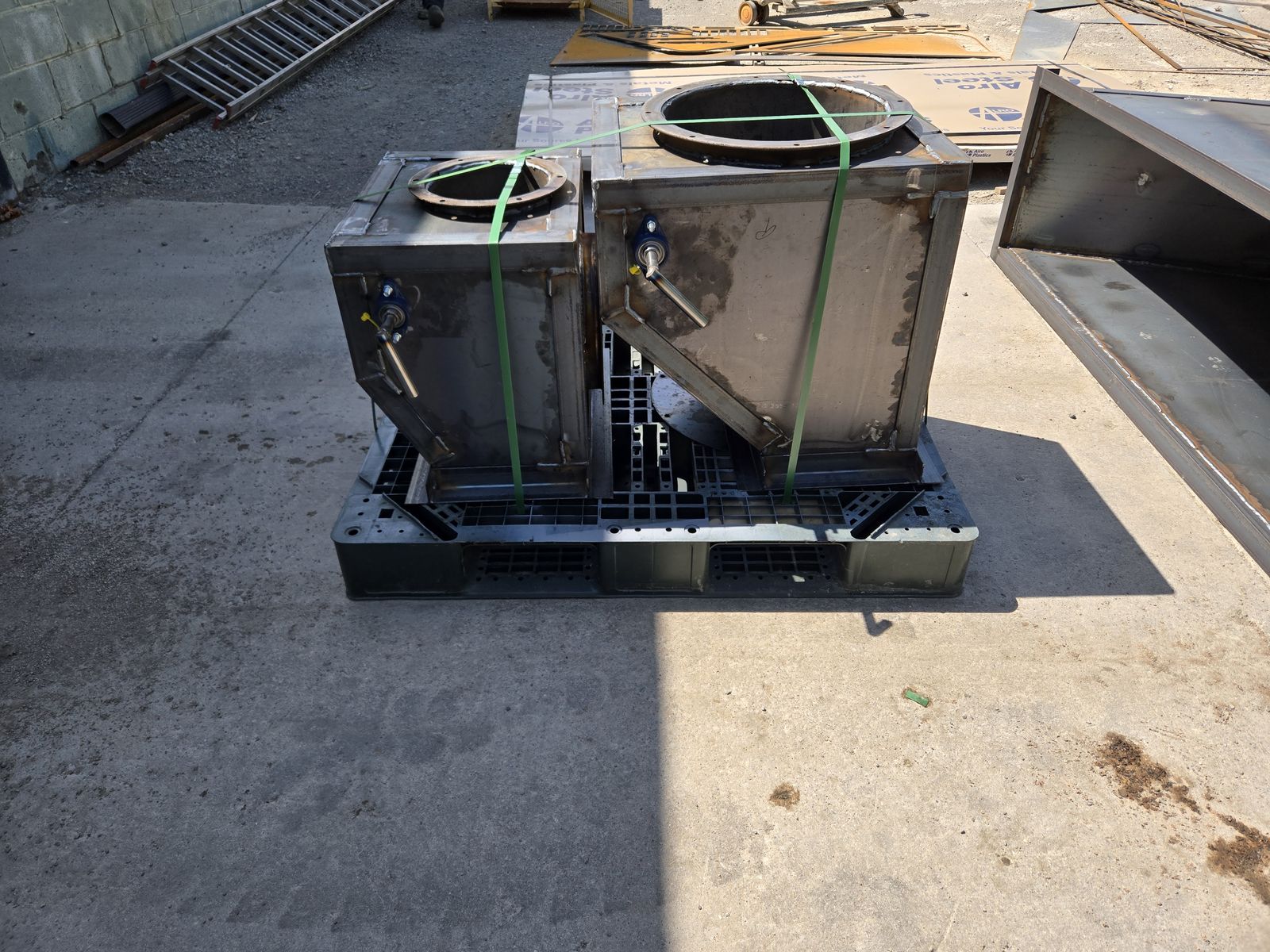 Steel hopper boxes with round bolt flanges and bearing-mounted shafts.