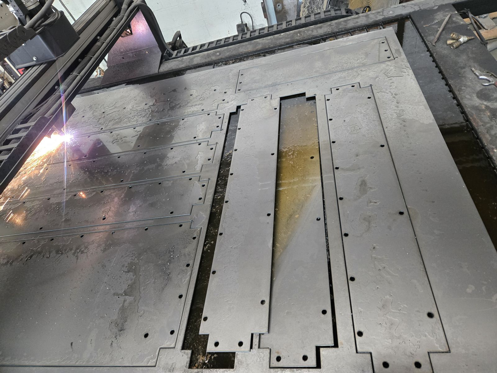 Plasma torch cutting long steel plates with bolt hole patterns.